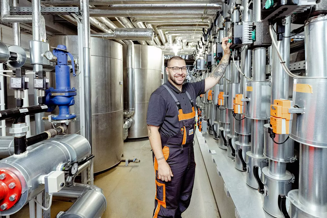 Un collaborateur masculin du service Facility Management devant l’installation de chauffage de Schl&uuml;ter-Systems.